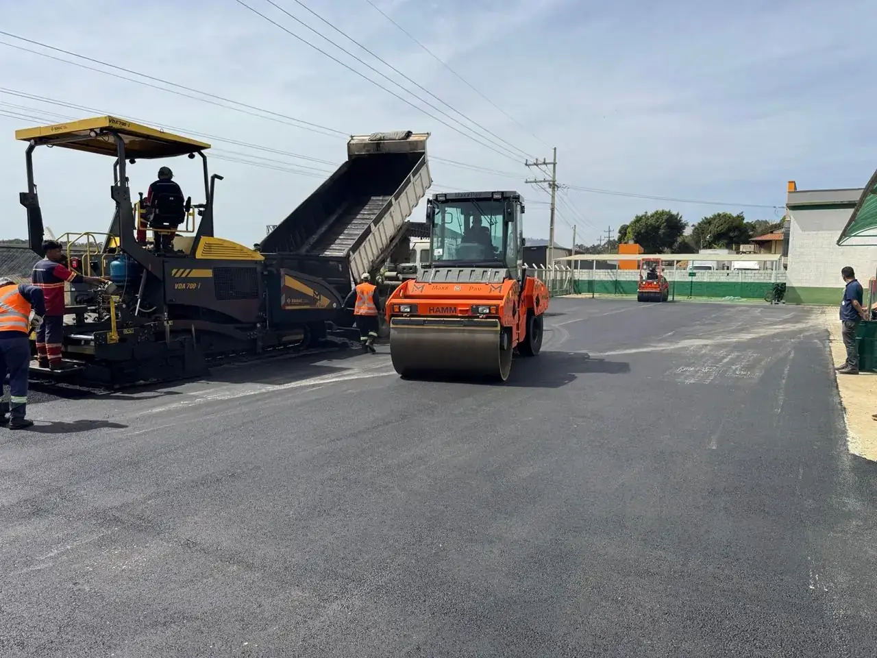 Aplicação de CBUQ com vibroacabadora, caminhão basculante e rolo compactador em pátio industrial