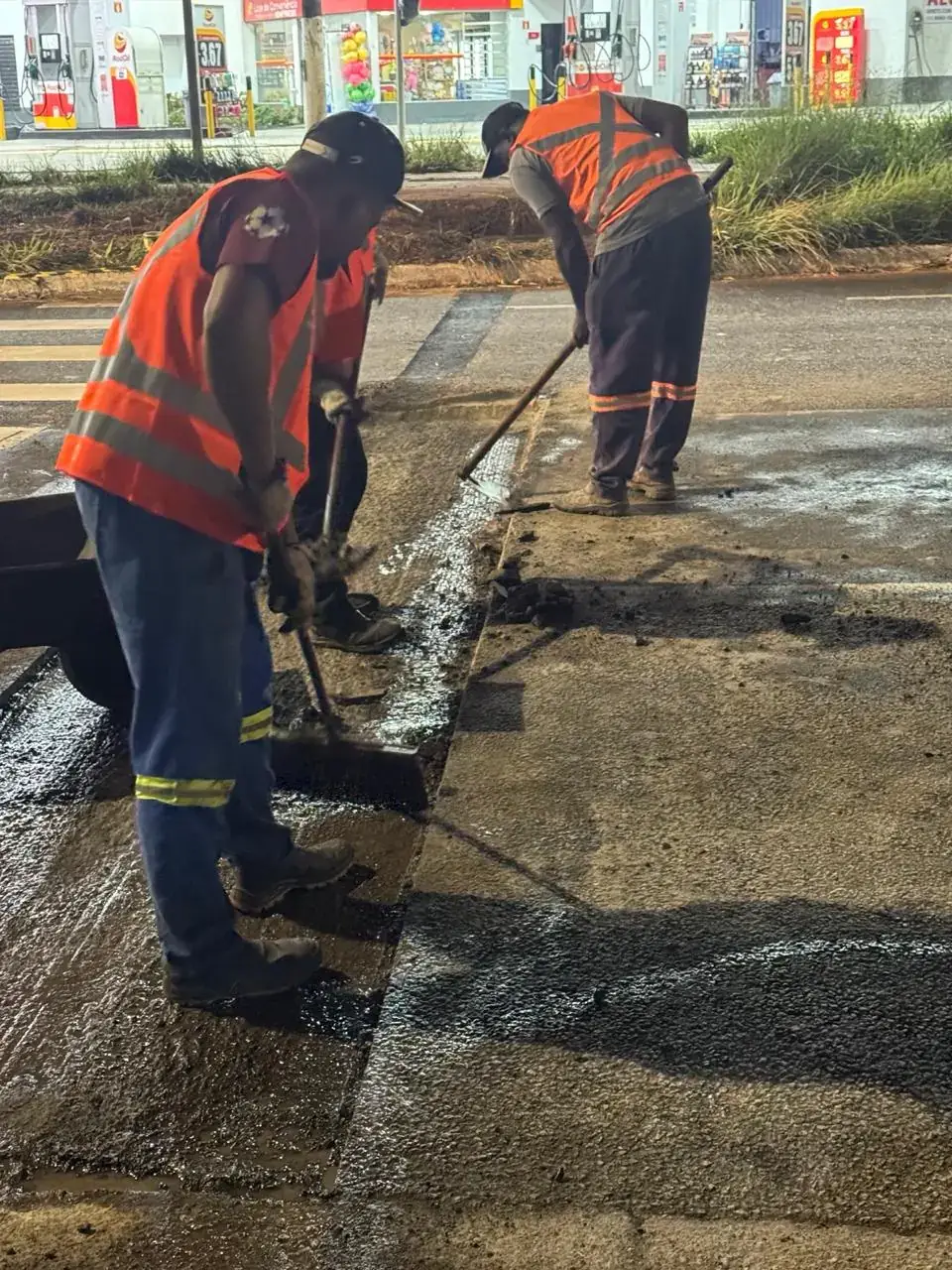 Equipe espalhando massa asfáltica em reparo localizado de pavimento